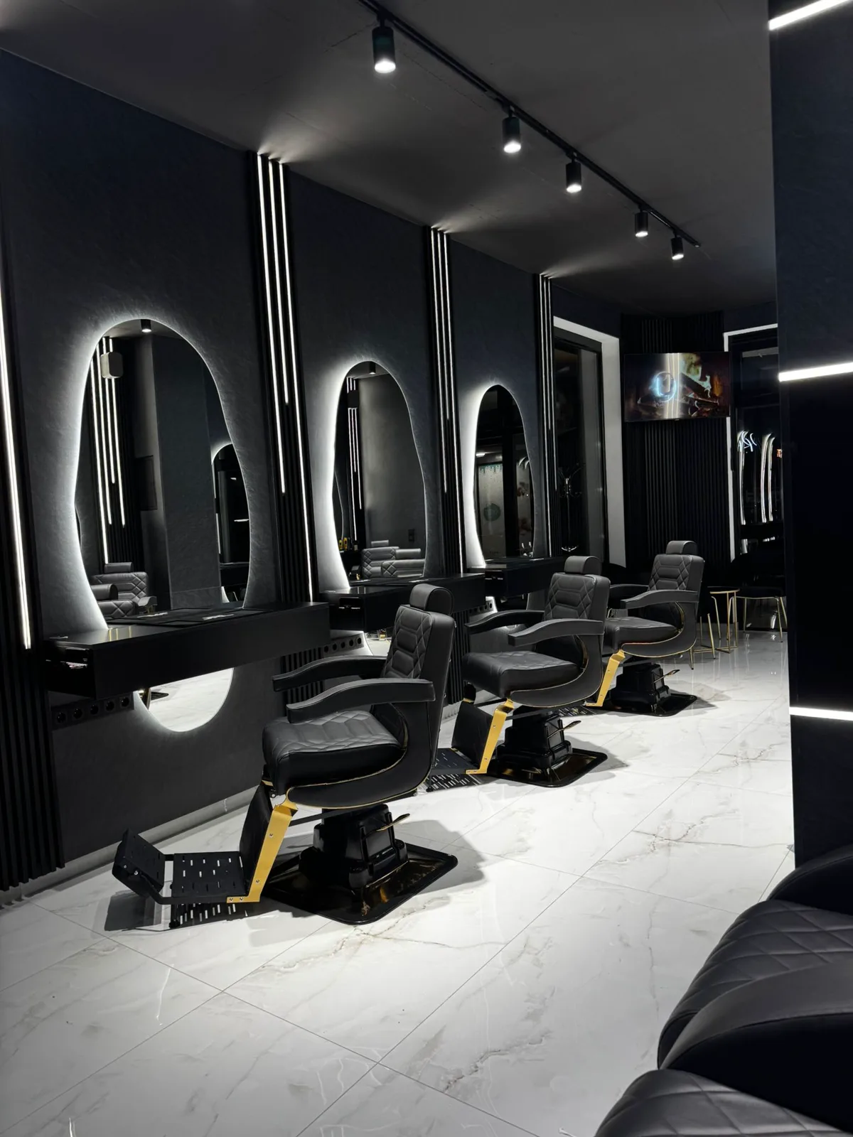 Unutrašnjost Prestige Hair Lounge salona u Sarajevu sa frizerskim stolicama, osvijetljenim ogledalima i radnim mjestima za šišanje i uređivanje.